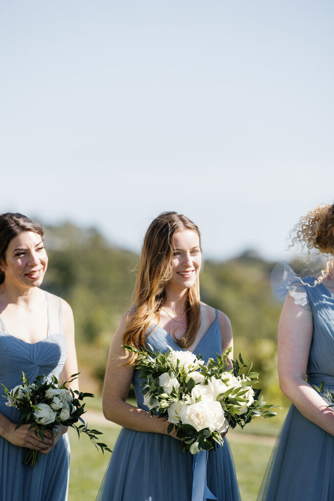 Bridesmaid in blue dress holding flowers and smiling