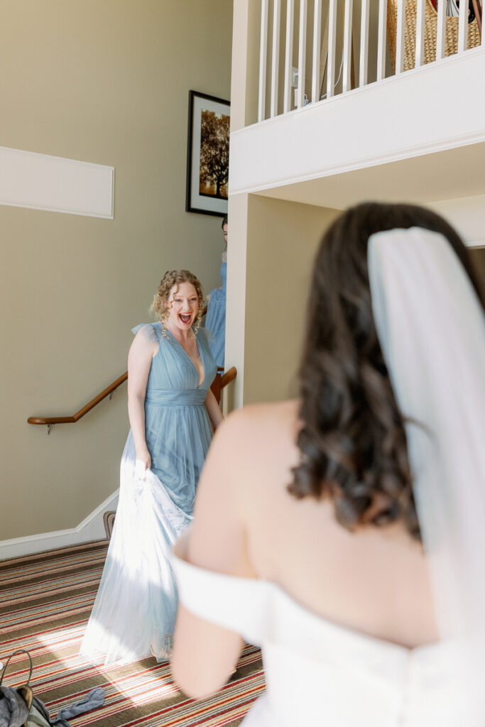 A bridesmaid coming around the corner and seeing the bride with a huge smile on her face