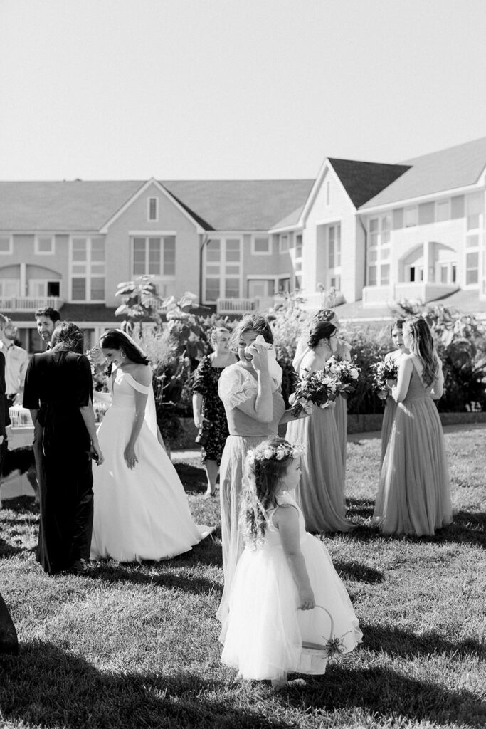 Bridesmaid wiping tears after a ceremony with other wedding guests nearby