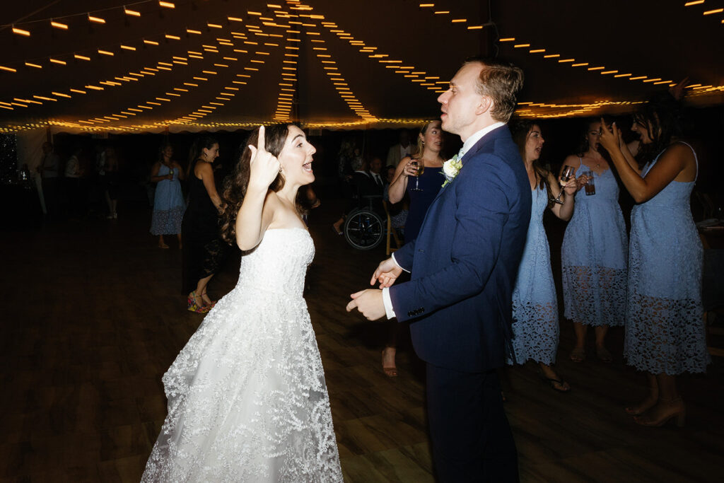 A bride and groom dancing under a canopy of string lights at their wedding reception