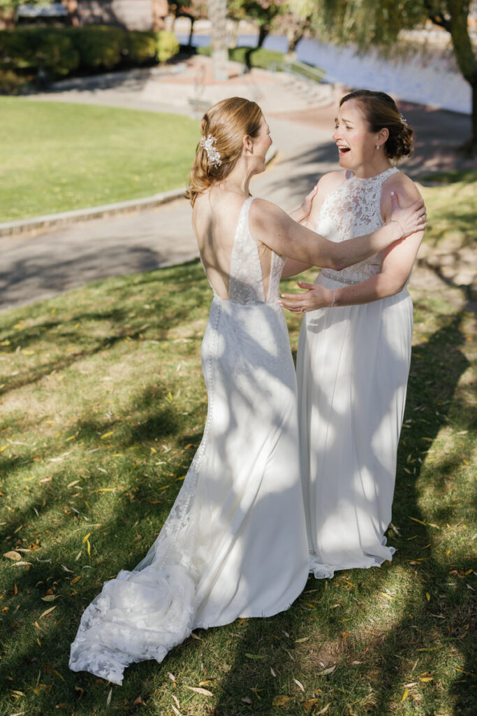 Two brides during their first look with big smiles on their face 