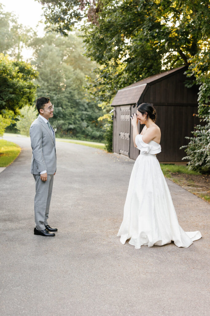 A bride and groom standing on a small road during their first look 