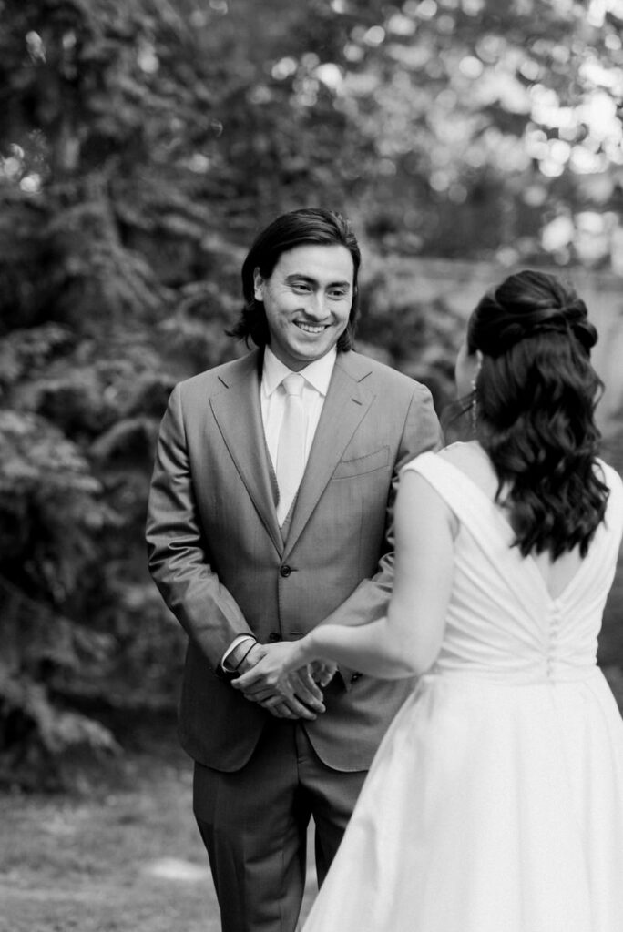 A groom smiling at a bride during their first look 