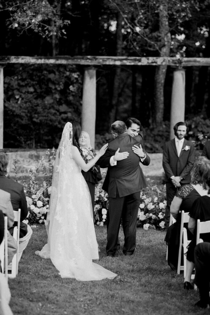 The bride's father hugs the groom