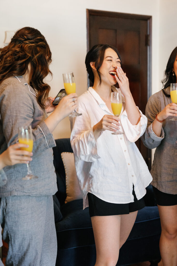 A bride laughs with her bridal party as they toast.